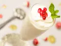 Creme double in einem Glas, garniert mit Granatapfelkernen und Minze. Ein Löffel liegt daneben.