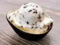 Ein Löffel cremiges Stracciatella-Eis mit zarten Schokoladenstückchen in einer Schale.