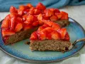 Ein saftiger glutenfreier Erdbeerkuchen mit frischen Erdbeeren und glänzender Tortenglasur auf einem blauen Teller.