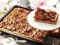 Ein saftiger Zwetschgenkuchen vom Blech, mit süßen Früchten und Zucker bestreut, wartet darauf, genossen zu werden.