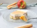 Ein Stück Apfel Schmand Kuchen mit Löffelbiskuits und einem Apfel im Hintergrund.