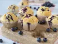 Saftige Blaubeer Muffins mit frischen Blaubeeren, auf einem Holzbrett arrangiert.
