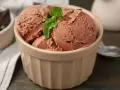 Schokoladeneis in einer Schale, garniert mit Minze. Dieses Eis ist ein Beweis dafür, was vollrahm ist: cremig, reichhaltig und unwiderstehlich.