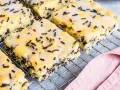 Saftiger Ameisenkuchen vom Blech, mit Zuckerguss und Schokostreuseln verziert, auf einem Kuchengitter.