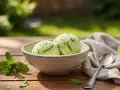 Zwei Kugeln Minz-Limetten-Eis in einer Schale, garniert mit Minze und Limettenschale. Perfekt, um den zuckergehalt messen.