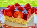 Ein saftiges Stück Erdbeerkuchen vom Blech, belegt mit frischen Erdbeeren und Tortenguss.
