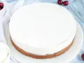 Ein köstlicher Kuchen mit Mascarpone-Creme, garniert mit frischen Kirschen und einem Schneebesen daneben.