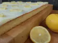Ein saftiger sizilianischer Zitronenkuchen, bedeckt mit weißer Glasur und Zitronenscheiben, daneben frische Zitronen.