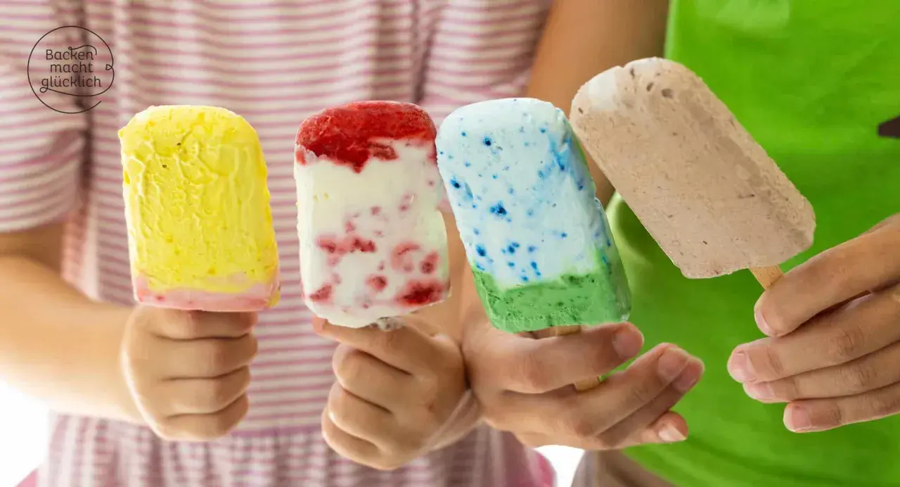 Vier Kinderhände halten bunte Eis am Stiel. Ein gelbes, ein Erdbeer-Vanille, ein blau-grünes und ein Schokoladen-Eis. Perfekt für heiße Tage!