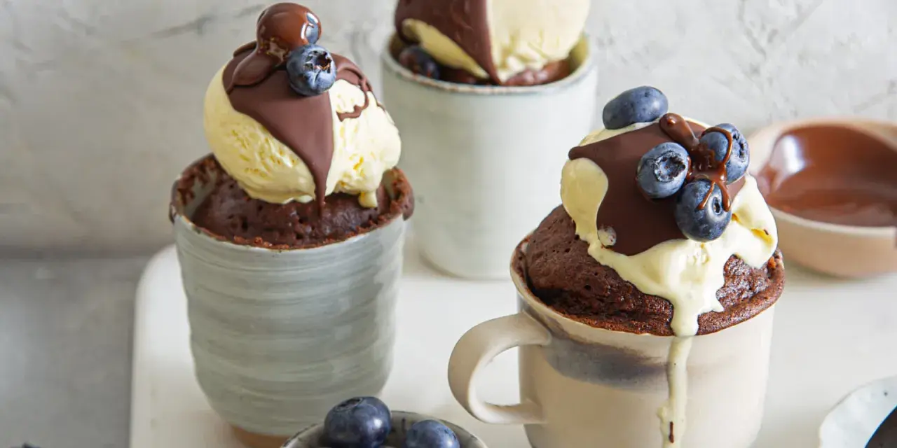 Schokoladiger Tassenkuchen mit Vanilleeis, Schokosauce und Blaubeeren. Ein schnelles Tassenkuchen Rezept für süße Momente.
