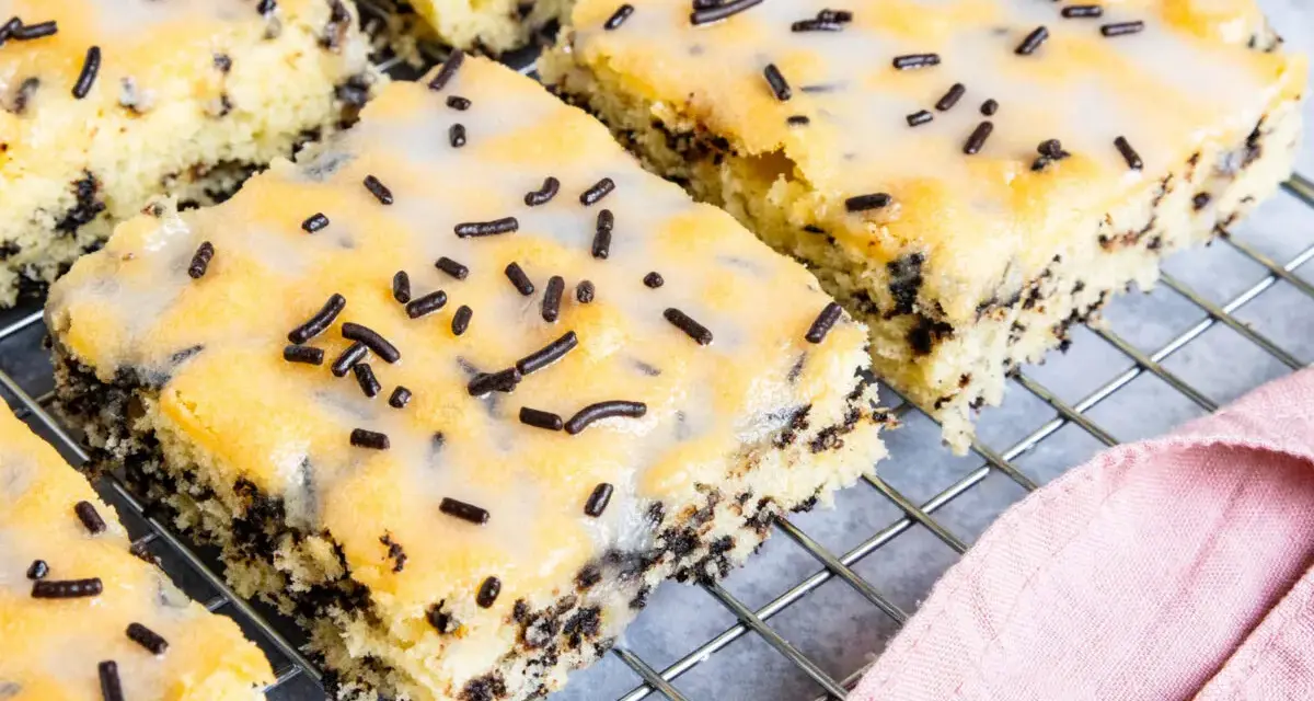 Saftiger Ameisenkuchen vom Blech, mit Zuckerguss und Schokostreuseln verziert, auf einem Kuchengitter.