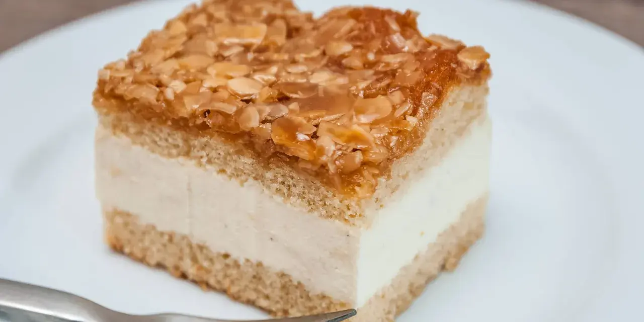 Ein Stück Bienenstich-Kuchen mit cremiger Füllung und karamellisierten Mandeln. Ein leckeres Rezept für den süßen Genuss.