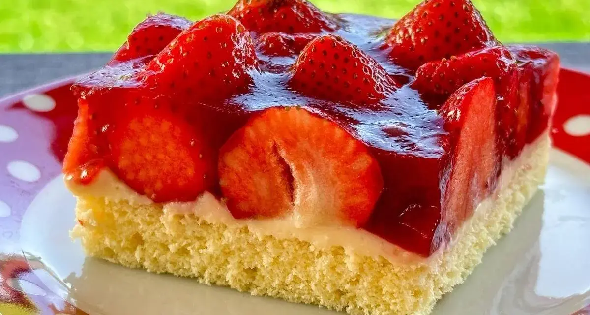 Ein saftiges Stück Erdbeerkuchen vom Blech, belegt mit frischen Erdbeeren und Tortenguss.