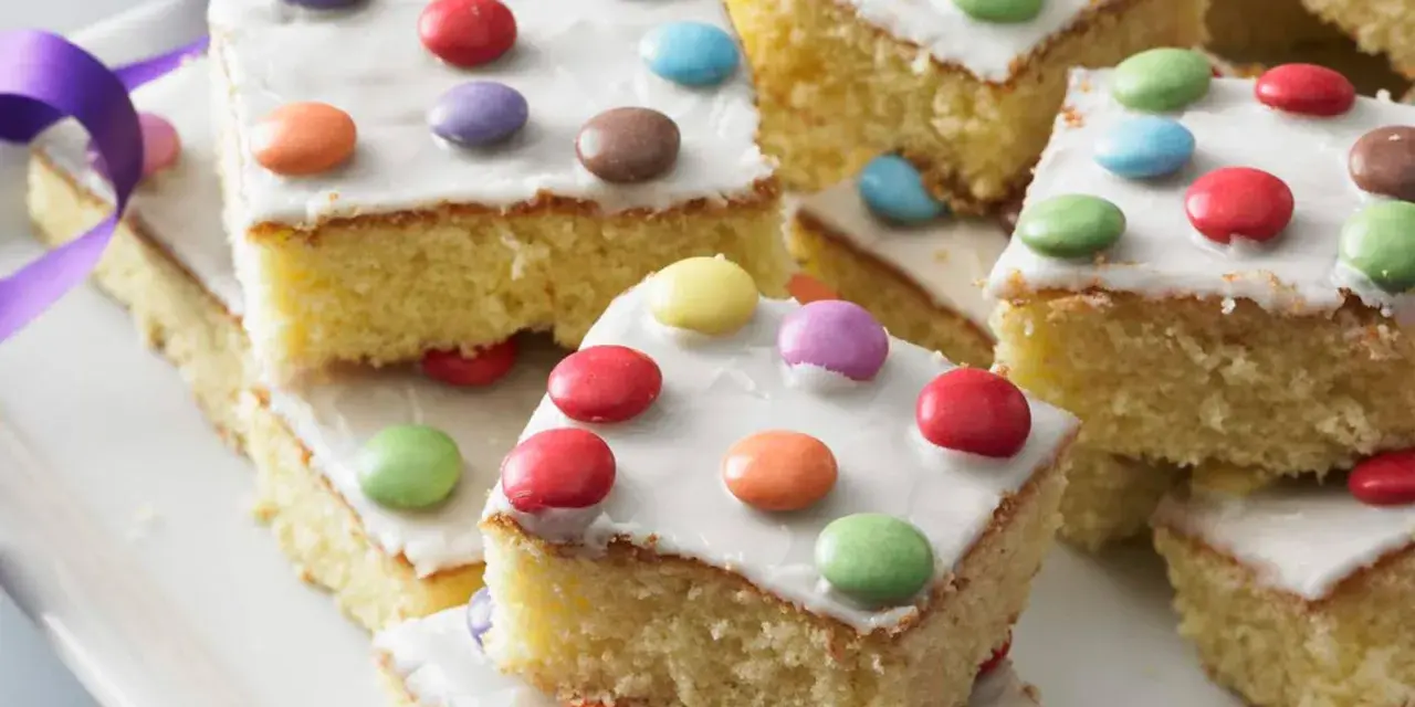 Bunter Fantakuchen-Rezept: saftige Kuchenstücke mit weißer Glasur und bunten Smarties. Perfekt für Kindergeburtstage!
