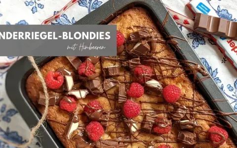 Kinderriegel-Blondies mit Himbeeren: Ein saftiger Kuchen, dekoriert mit Schokolade und frischen Beeren. Perfekt für das Blondies Rezept!