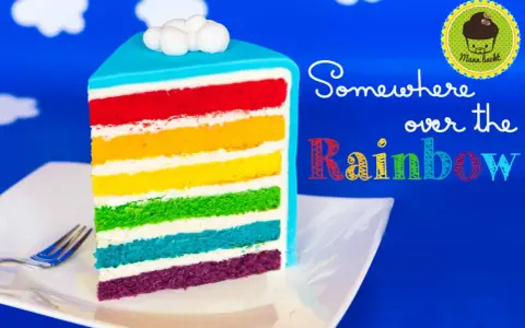 Ein Stück regenbogen kuchen mit bunten Schichten und Wolken-Deko.