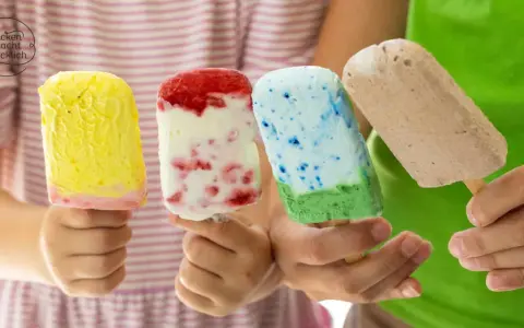 Vier Kinderhände halten bunte Eis am Stiel. Ein gelbes, ein Erdbeer-Vanille, ein blau-grünes und ein Schokoladen-Eis. Perfekt für heiße Tage!