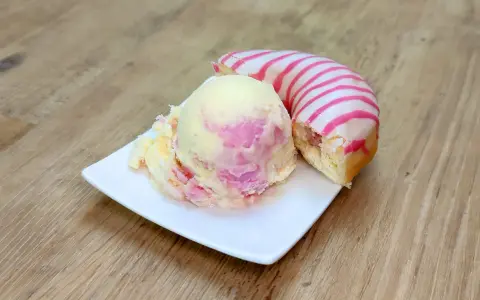 Ein cremiges Eis mit rosa Schlieren neben einem Donut mit rosa Streifen. Perfekt für eine süße Auszeit!