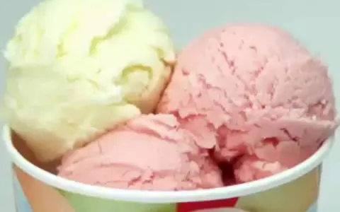 Drei Kugeln Eis in einem Becher: eine hellgelbe und zwei rosafarbene. Verschiedene eis arten für süße Momente.