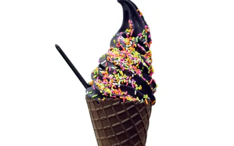 Schwarzes Eis in einer Waffel, bestreut mit bunten Streuseln. Ein schwarzer Löffel steckt darin.