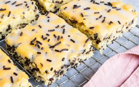 Saftiger Ameisenkuchen vom Blech, mit Zuckerguss und Schokostreuseln verziert, auf einem Kuchengitter.