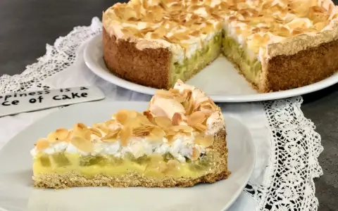 Ein köstlicher Rhabarberkuchen mit Pudding und Baiser, bestreut mit Mandelblättchen. Ein Stück Glück auf einem Teller.