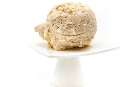 Eine Kugel Milchreis Eis auf einem weißen Teller. Cremig und mit Stückchen, ein Genuss!