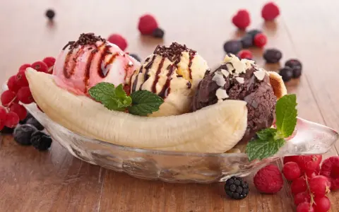 Ein klassisches Banana Split Eis mit drei Kugeln Eis, garniert mit Beeren und Schokostreuseln.