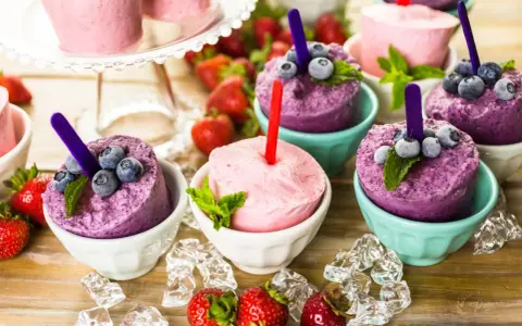 Erfrischendes Eis in Schalen, perfekt zum **Crème double selber machen**. Blaubeeren und Erdbeeren garnieren die bunten Leckereien.
