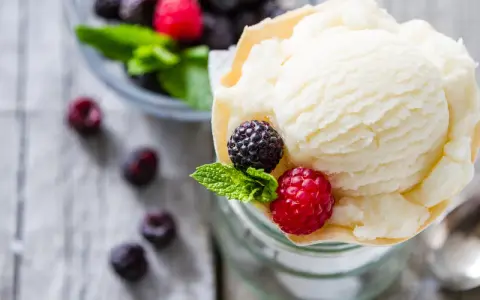 Cremiges Joghurteis selber machen: Eine Portion mit frischen Beeren und Minze, daneben eine Schüssel voller Brombeeren und Himbeeren.