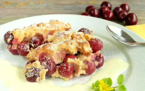 Zwei Portionen Kirschenmichel, ein köstliches Dessert, serviert mit Vanillesauce und bestäubt mit Puderzucker. Ein perfektes Kirschenmichel Rezept.