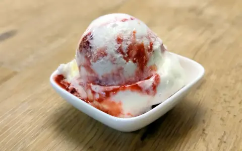 Ein Eisbecher mit Erdbeersoße, der zum sofortigen Genuss einlädt. Ein wahrer "Ed von Schleck" Moment!