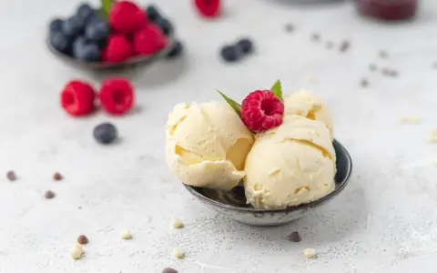 Cremiges Vanilleeis, garniert mit einer Himbeere. Perfekt, um eis ohne zucker selber machen zu lernen.