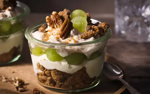 Ein köstliches Trauben-Cookie-Dessert im Glas, geschichtet mit cremigem Joghurt, knackigen Keksen und saftigen Trauben. Garniert mit Pekannüssen.
