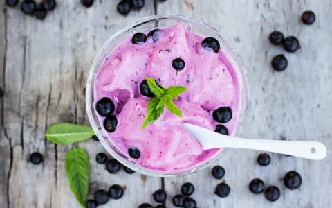 Ein Schälchen mit cremigem Johannisbeer Eis, garniert mit frischer Minze und ganzen Beeren.