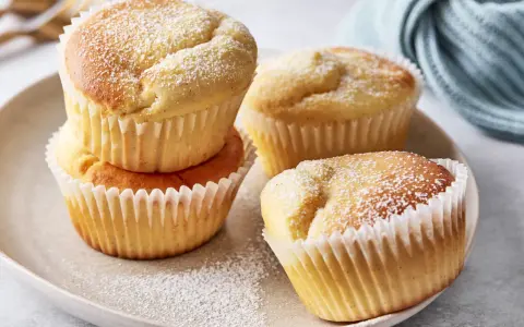 Saftige Quark Muffins, bestäubt mit Puderzucker, auf einem Teller.