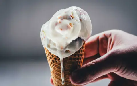 Eine Hand hält ein schmelzendes Rhabarber-Eis in einer Waffel.