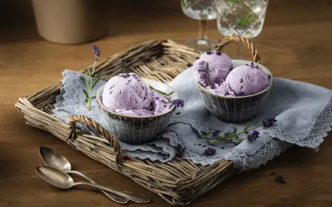 Zwei Schalen mit cremigem Lavendeleis, garniert mit Lavendelblüten. Ein köstliches Lavendeleis Rezept zum Nachmachen.