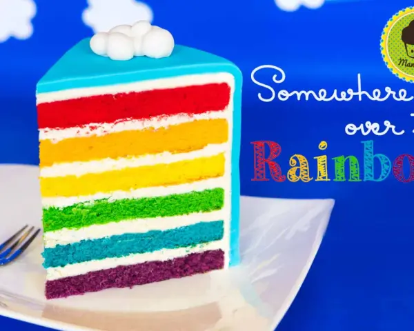 Ein Stück regenbogen kuchen mit bunten Schichten und Wolken-Deko.