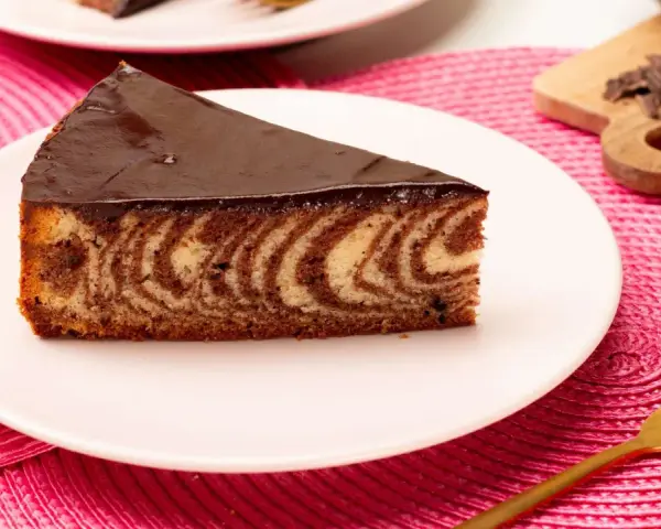 Ein Stück saftiger Zebrakuchen mit Schokoladenglasur auf einem Teller. Dieses Zebrakuchen Rezept ist ein Klassiker.