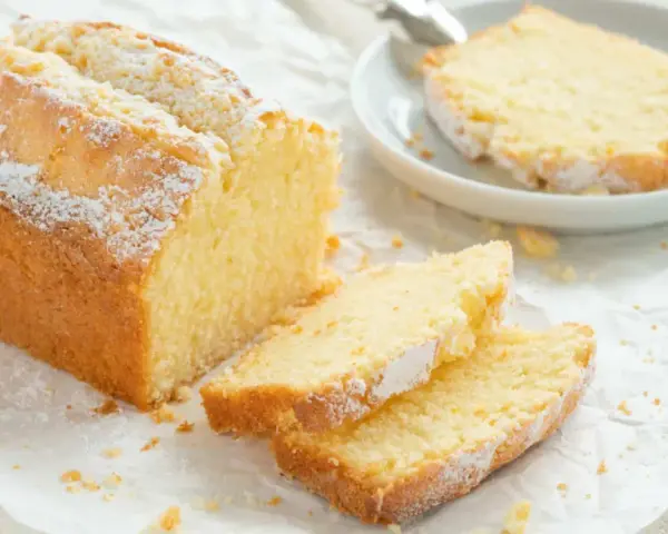 Ein goldbrauner Sandkuchen, bestäubt mit Puderzucker, wartet darauf, nach diesem einfachen Sandkuchen Rezept gebacken zu werden.