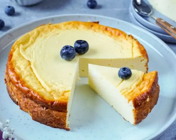 Ein köstlicher, gesunder Kuchen mit Blaubeeren, der auf einem Teller serviert wird. Ein Stück ist bereits herausgeschnitten.