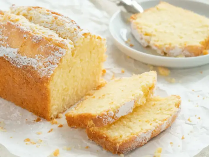 Ein goldbrauner Sandkuchen, bestäubt mit Puderzucker, wartet darauf, nach diesem einfachen Sandkuchen Rezept gebacken zu werden.