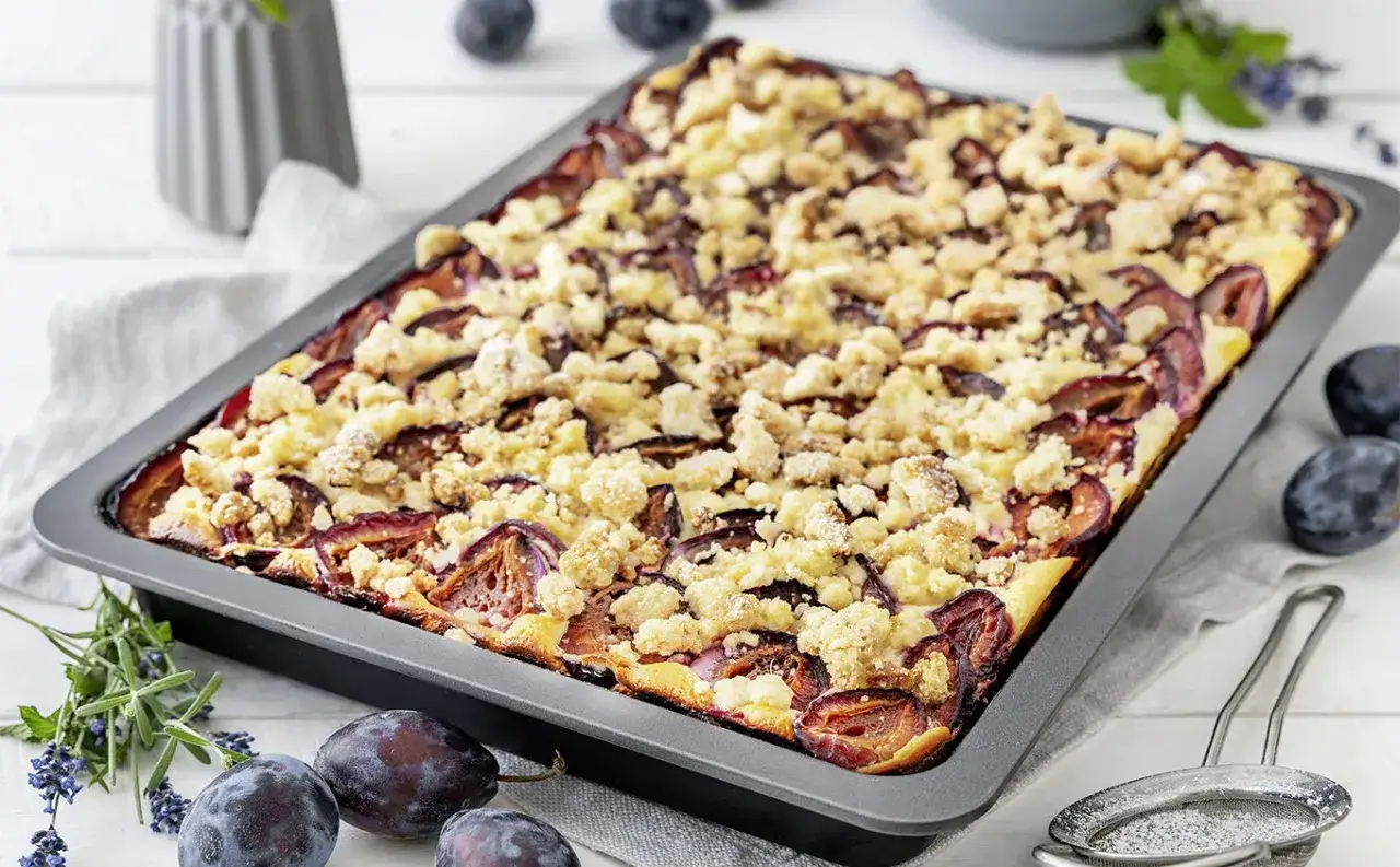 Ein saftiger Zwetschgenkuchen vom Blech mit Streuseln, frisch aus dem Ofen.