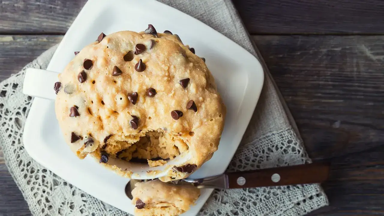 Leckerer Tassenkuchen mit Schokostückchen, perfekt für ein schnelles Tassenkuchen Rezept. Ein Löffel zeigt die saftige Konsistenz.