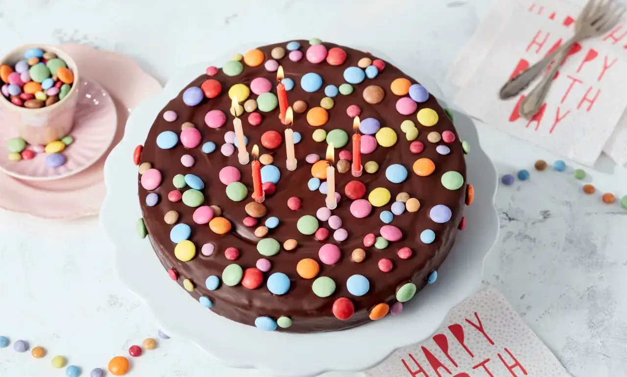 Schokokuchen mit bunten Smarties und Kerzen, perfekt für Kinder. Ein süßer Traum für jeden Geburtstag!