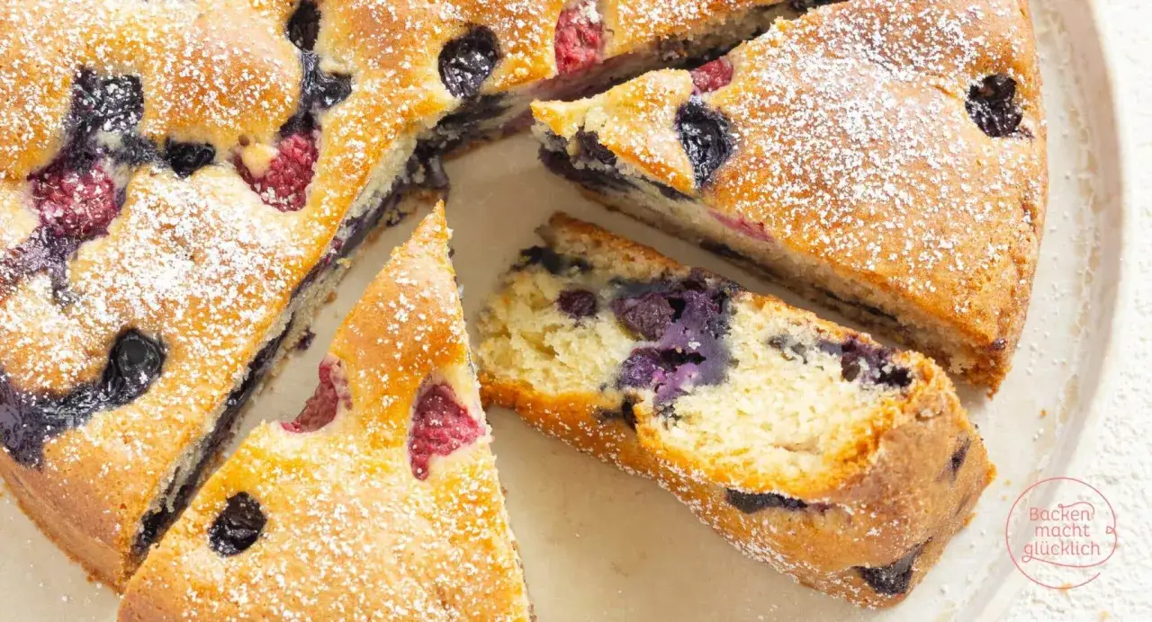 Saftiger veganer Kuchen mit Blaubeeren und Himbeeren, bestäubt mit Puderzucker. Ein Genuss für alle!