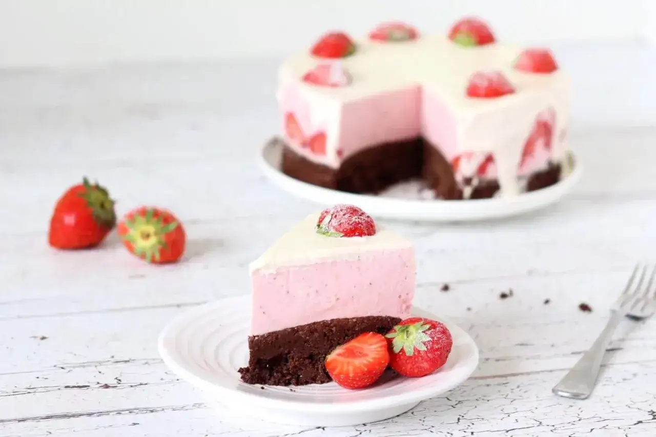Ein Stück saftiger low carb kuchen mit Erdbeer-Mousse und Schokoboden, garniert mit frischen Erdbeeren.