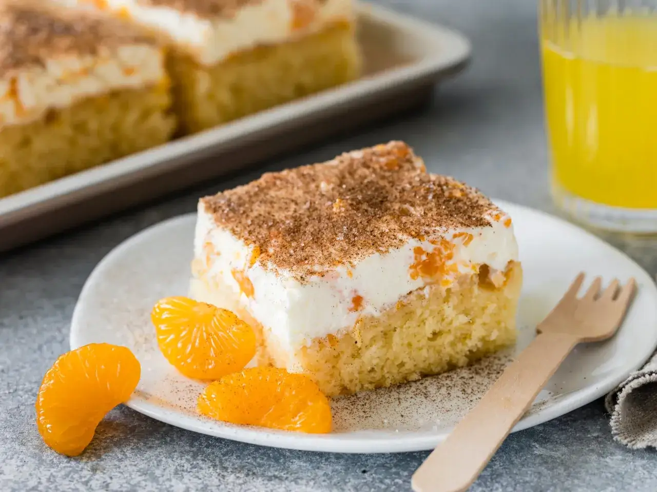 Ein Stück saftiger Fantakuchen mit Mandarinen und Sahne, bestreut mit Zimt. Perfekt für ein Fantakuchen Rezept.
