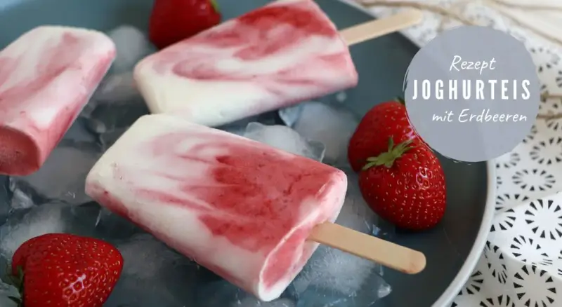 Erfrischendes Erdbeereis am Stiel mit Joghurt und frischen Erdbeeren auf Eiswürfeln.